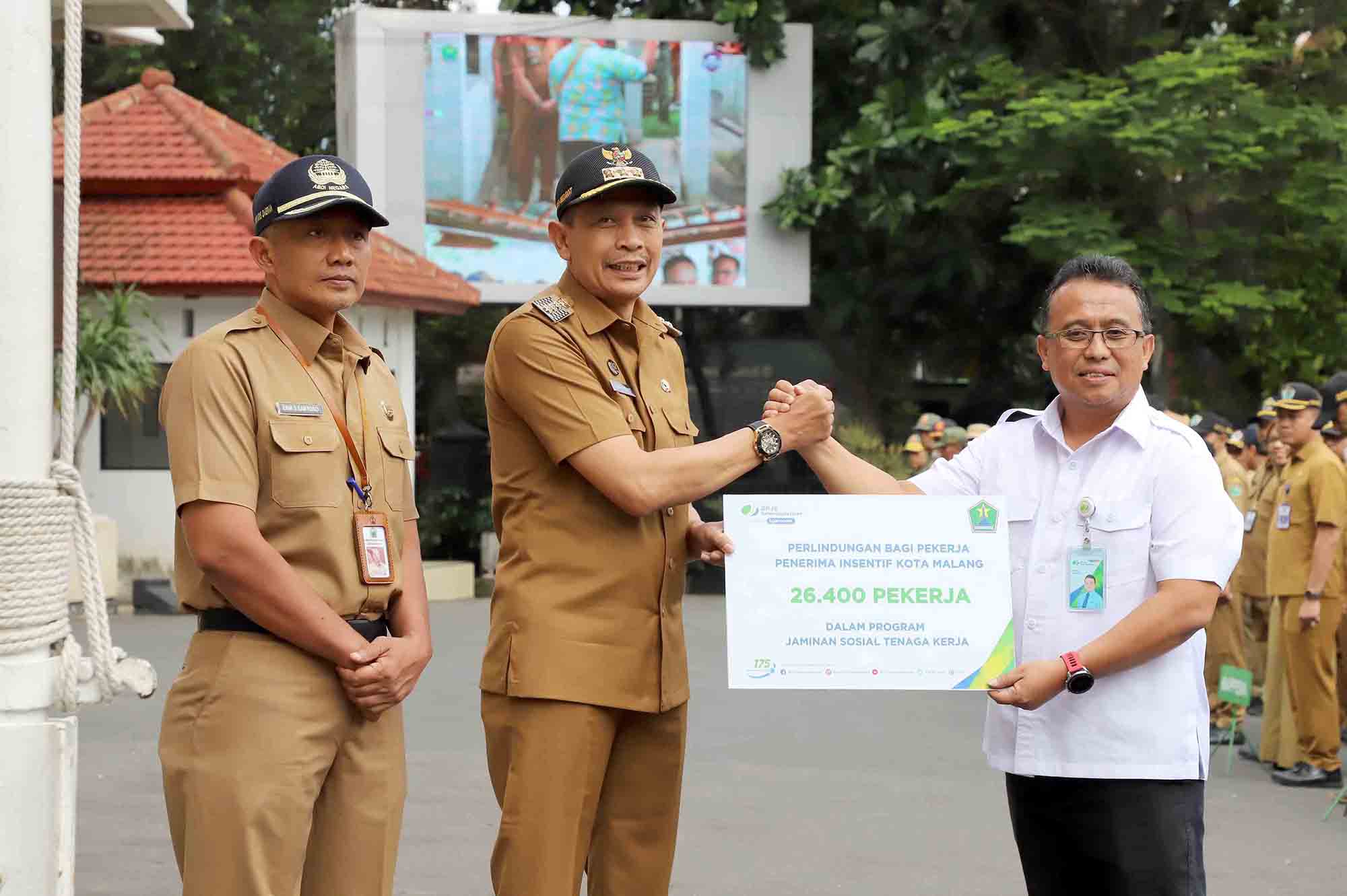 Penjabat Wali Kota Malang Wahyu Hidayat menyerahkan kepesertaan Jamsostek usai Apel Pagi ASN di Halaman Balai Kota Malang, Senin (18/3). Foto: Dok. Bagian Protokol dan Komunikasi Pimpinan Kota Malang