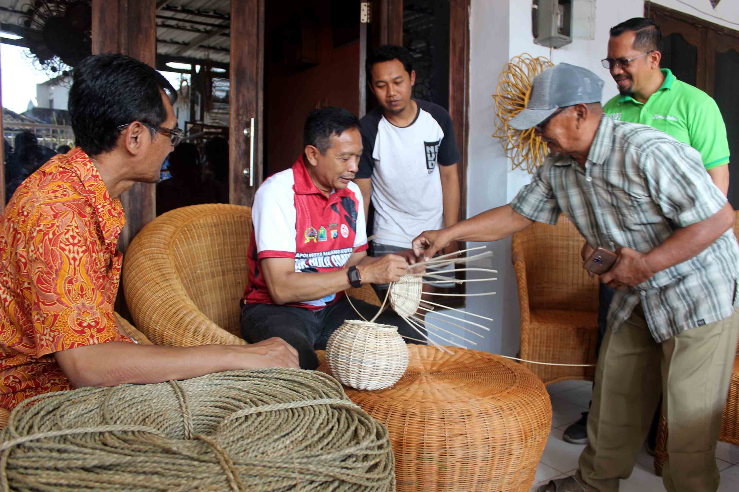 Penjabat Wali Kota Malang Wahyu Hidayat (kedua dari kiri) menganyam rotan saat mengunjungi sentra industri kerajinan rotan di Jalan Bulu Tangkis, Kelurahan Tasikmadu, Kecamatan Lowokwaru, Kota Malang, Minggu (16/6). Foto: Tugusatu/Bagus Suryo