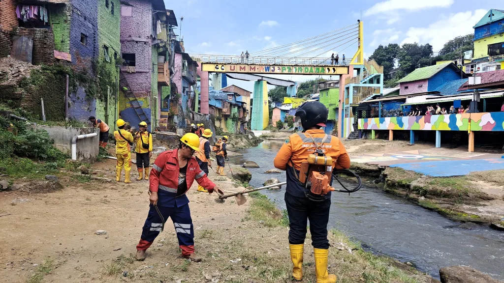 Petugas pramu kebersihan DLH Kota Malang bergotong royong membersihkan lingkungan sekitar Sungai Brantas di Kampung Warna Warni, Minggu (21/7). Foto: Dok. Pokdarwis Kota Malang