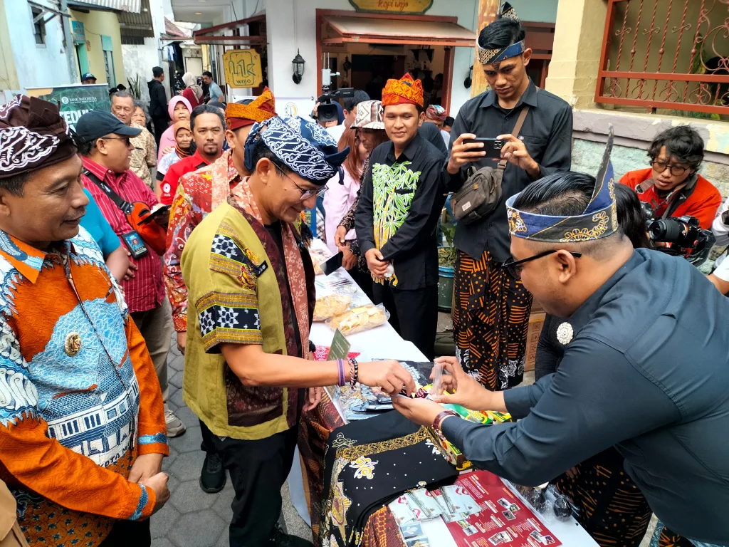 Kepala Desa Bejijong, Kecamatan Trowulan, Kabupaten Mojokerto, Pradana Tera Mardiatna, menunjukkan kerajinan cor kuningan kepada Menparekraf Sandiaga Uno di Kayutangan Heritage, Malang, Minggu (28/7). Foto: Tugusatu/Bagus Suryo