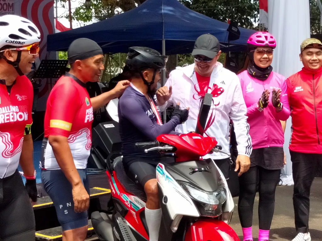 Penjabat Wali Kota Malang Iwan Kurniawan (jaket putih) dan Sekretaris Daerah Kota Malang Erik Setyo Santoso (kedua dari kiri) menyalami peraih hadiah motor Pedalling For Freedom, Minggu (25/8). Foto: Tugusatu/Bagus Suryo