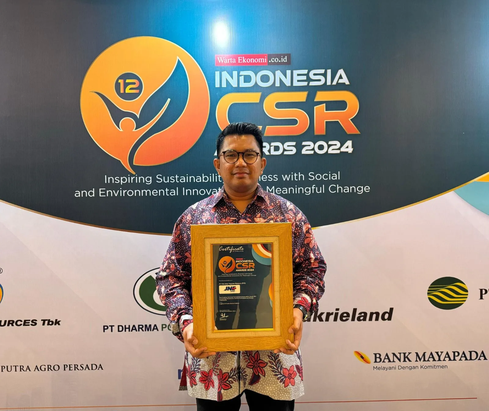 Media Communication Dept Head JNE,  Kurnia Nugraha, menunjukkan penghargaan yang diterima perusahaan, yakni Indonesia CSR Award 2024. Istimewa