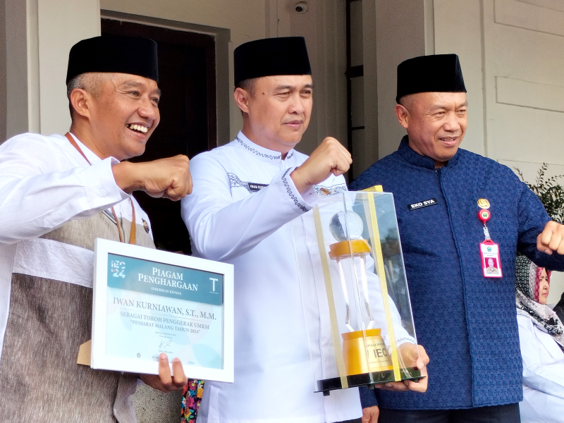 Penjabat Wali Kota Malang Iwan Kurniawan (tengah) menerima penghargaan sebagai tokoh penggerak UMKM saat Apel Hari Santri 2024 di Balai Kota Malang, Selasa (22/10). Iwan didampingi Sekda Kota Malang Erik Setyo Santoso (kiri) dan Kadiskopindag Kota Malang Eko Sri Yuliadi (kanan). Foto: Tugusatu/Bagus Suryo