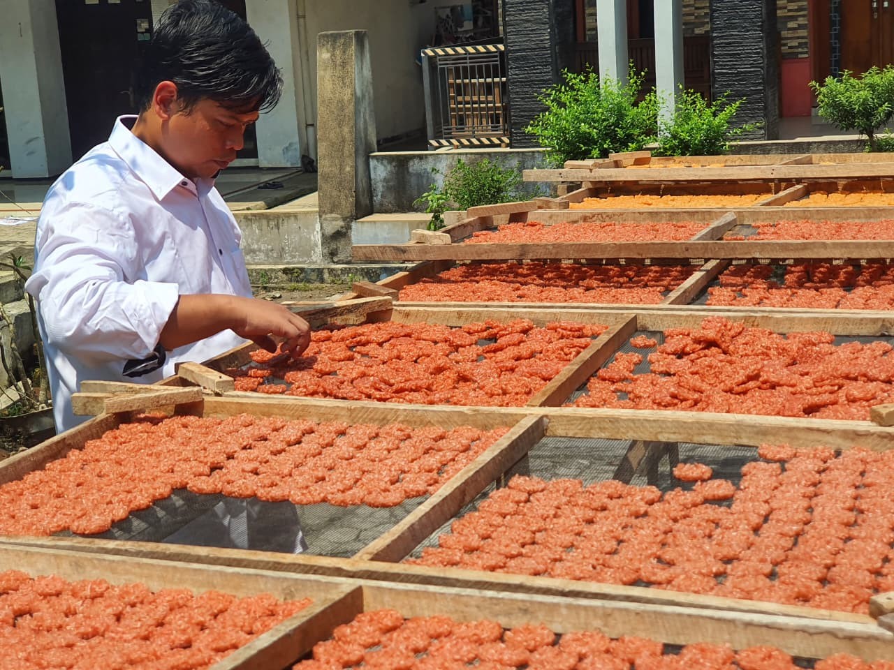 Karyawan Rengginang Kencana tengah membalik rengginang yang tengah dijemur  